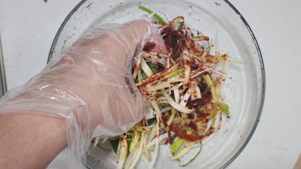 Tossing shredded scallions lightly with soy sauce, vinegar, and sesame oil dressing