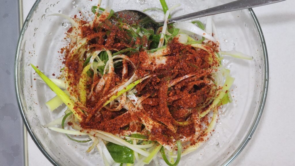 Tossing shredded scallions lightly with soy sauce, vinegar, and sesame oil dressing