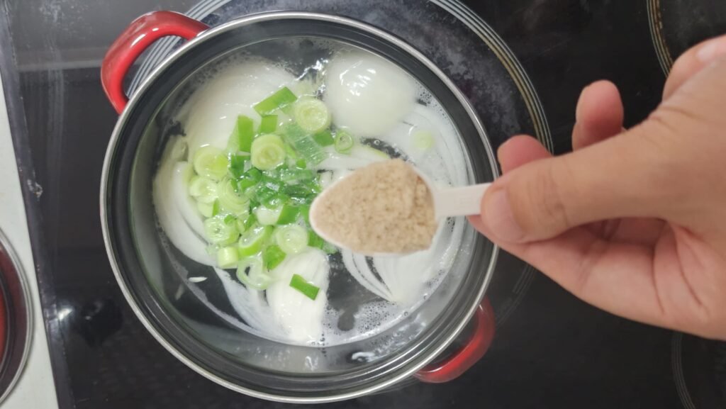 Adding chicken bouillon powder to season the egg drop soup