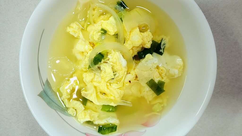 Finished warm Korean egg drop soup topped with chopped green scallions and black pepper