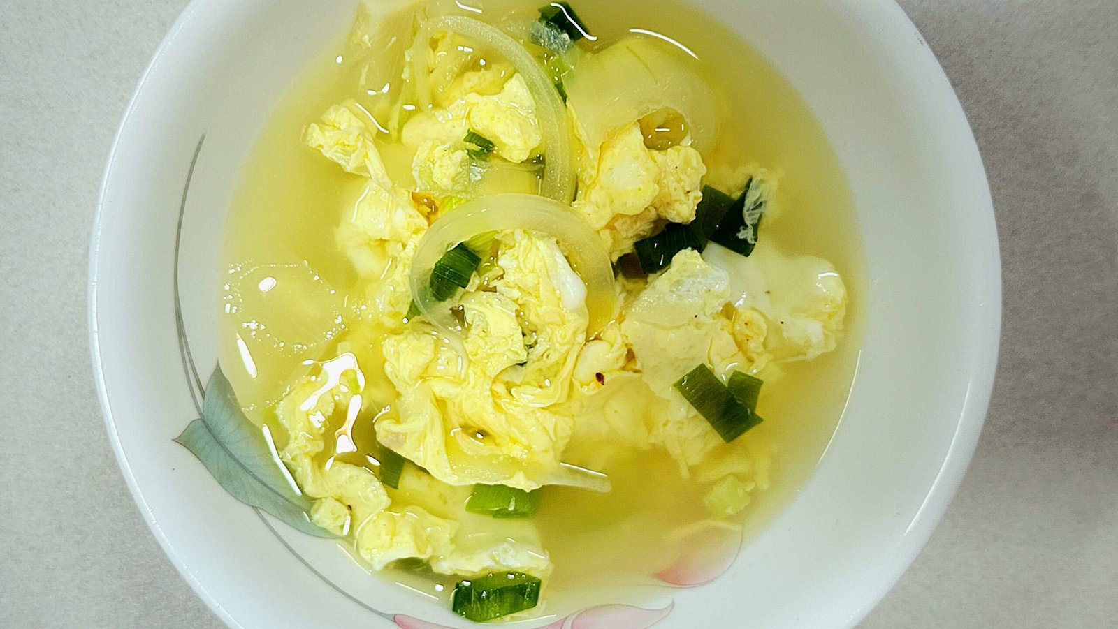 Finished warm Korean egg drop soup topped with chopped green scallions and black pepper