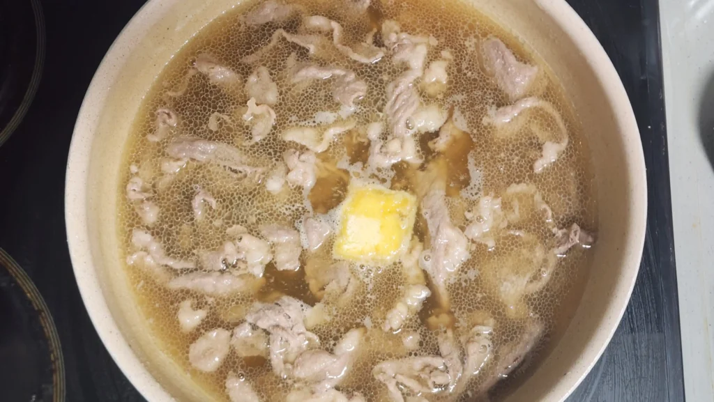 Adding water and seasonings to the beef in a pot