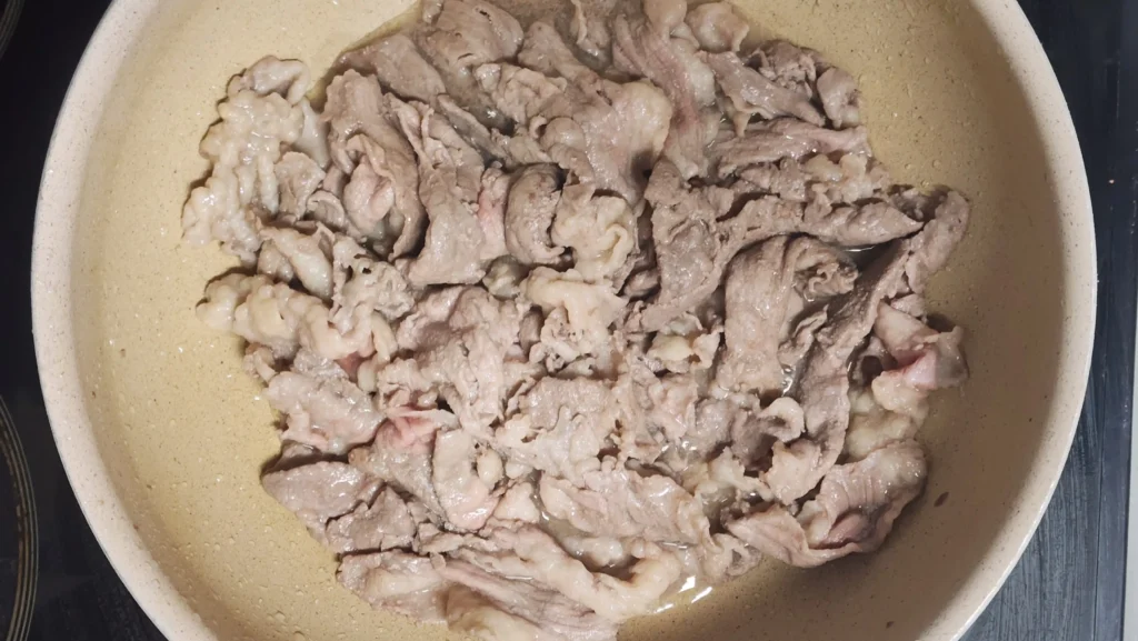 Stir-frying thinly sliced beef brisket in a pan over medium-high heat until no longer pink