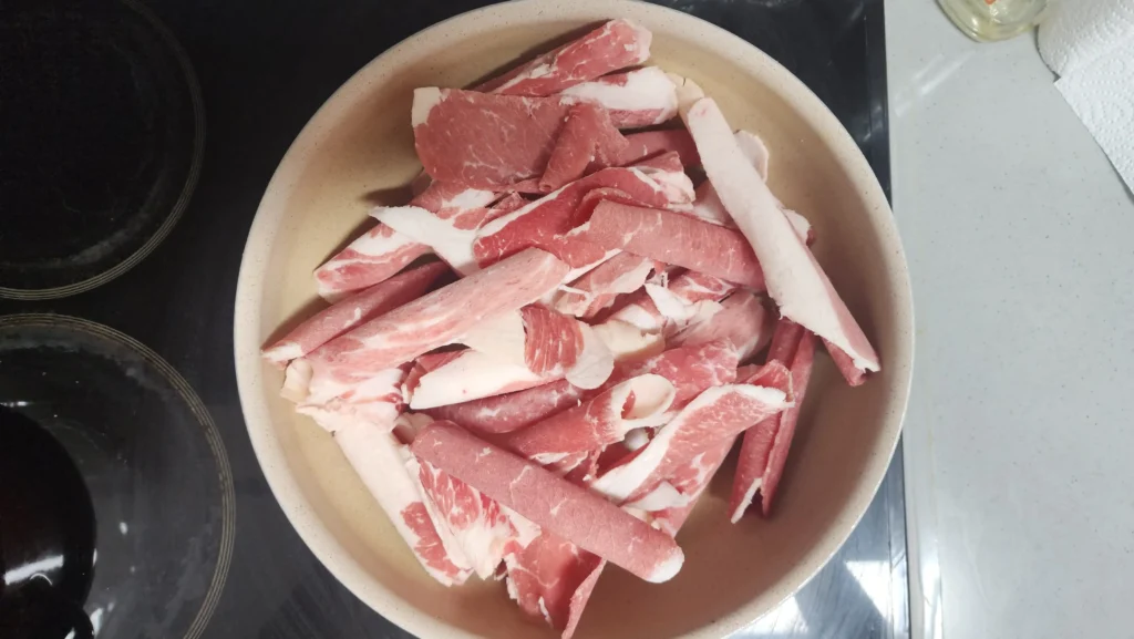 Stir-frying thinly sliced beef brisket in a pan over medium-high heat until no longer pink