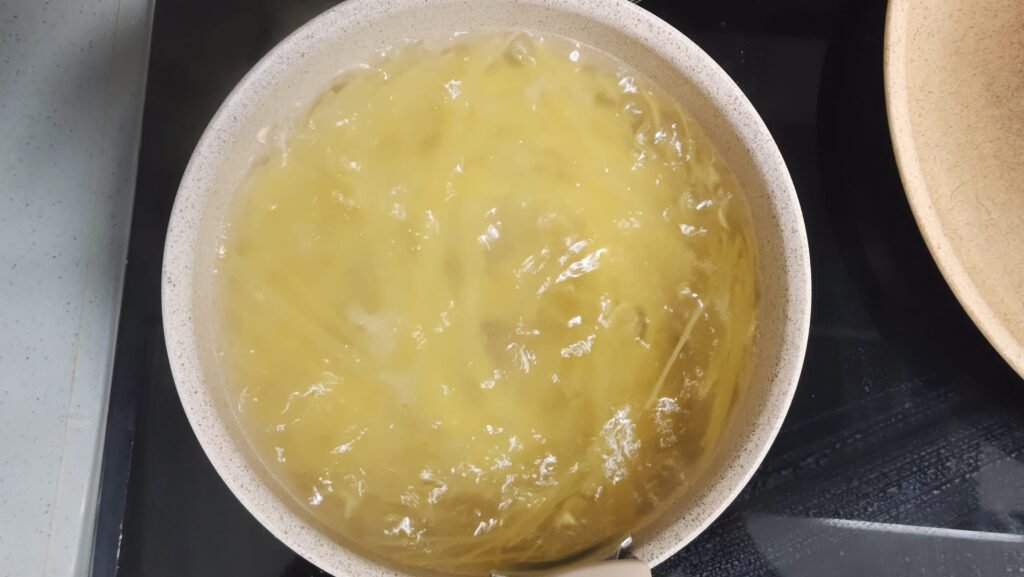 Boiled capellini noodles drained and spread out in a wide bowl to air-cool without rinsing in cold water