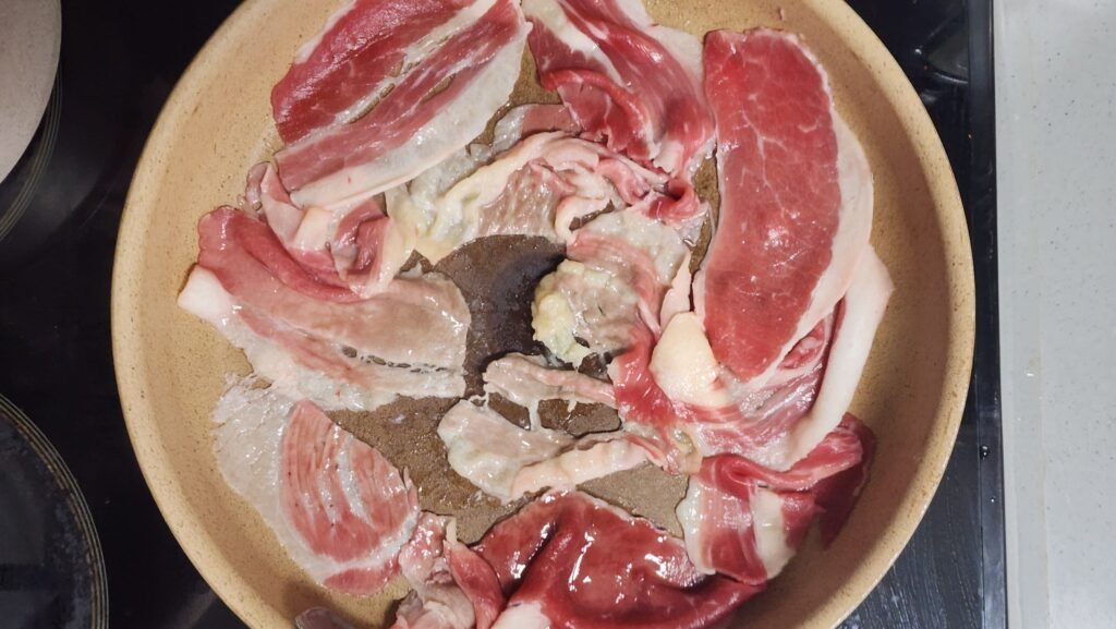 Thinly sliced beef brisket searing in a dry skillet without oil until lightly crisp and browned