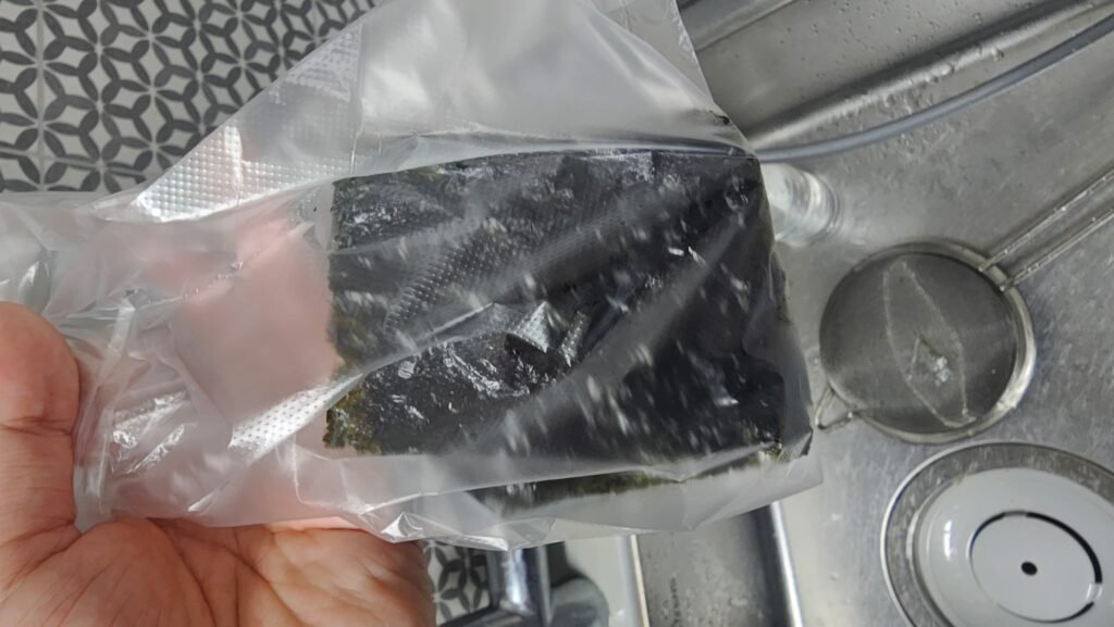 Crush the seasoned seaweed directly inside the bag with your hands into small flakes.