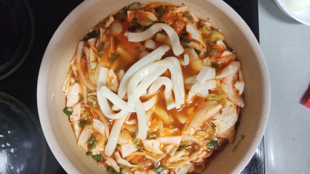 Simmering drained tteok in the spicy rabokki sauce