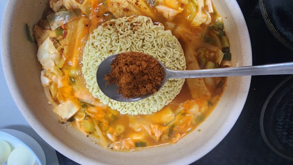 Cooking ramen noodles and boiled eggs in the bubbling rabokki sauce