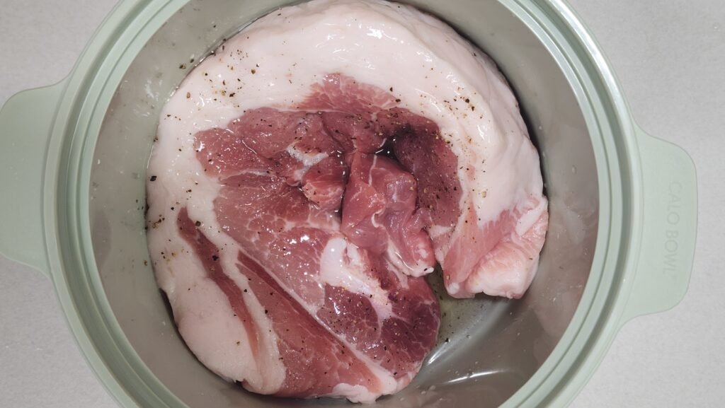 Marinating scored pork belly with beer, salt, and black pepper in a glass dish