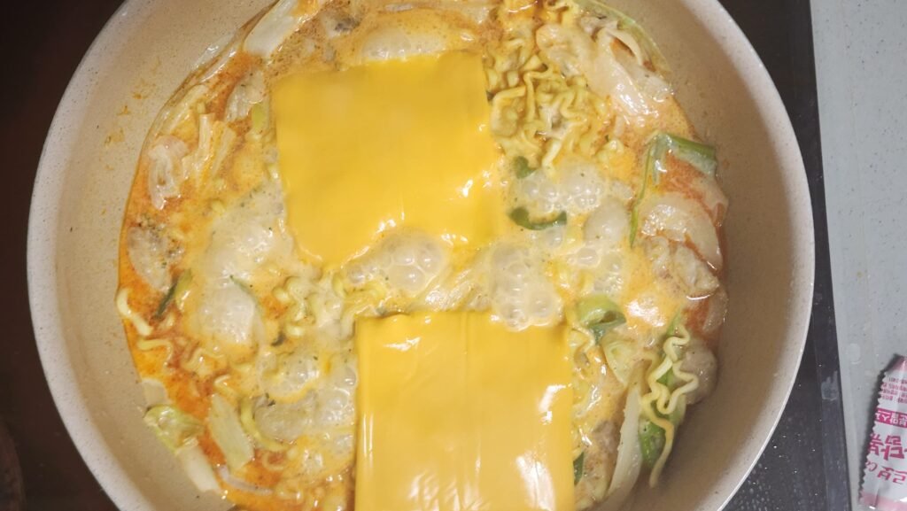 Adding two slices of cheddar after cooking the noodles for about 2 minutes, then cooking for about 3 more minutes.