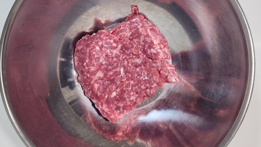 Ground beef with soy sauce, mirin, sugar, and minced garlic in a bowl.