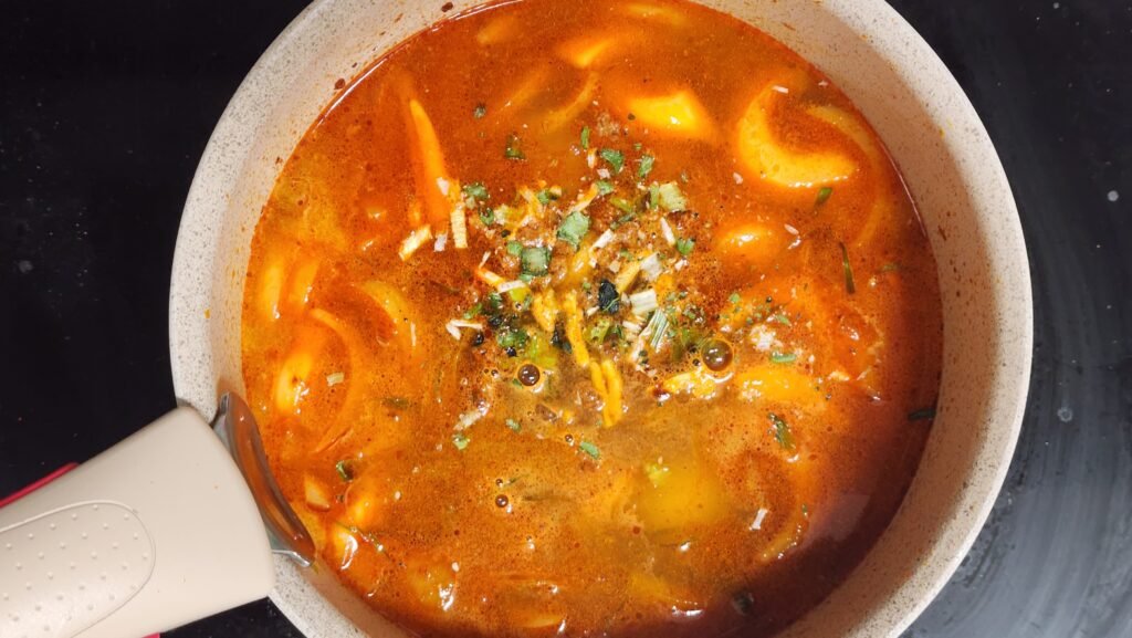 Adding 800ml water and Shin Ramyun seasoning packets to the stir-fried vegetables.