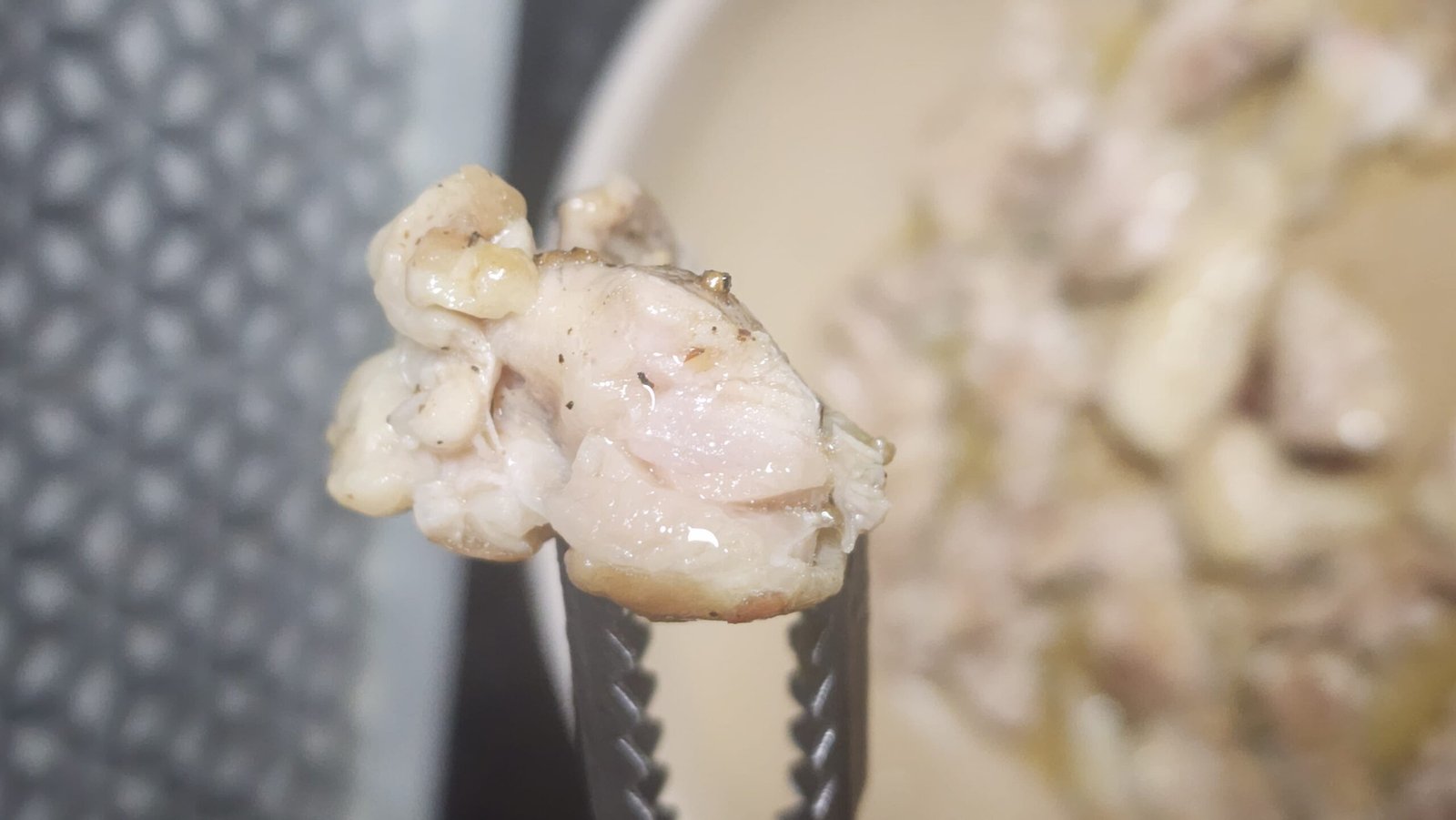 Cutting into the chicken thigh with kitchen scissors to check the inside while it is partially cooked.