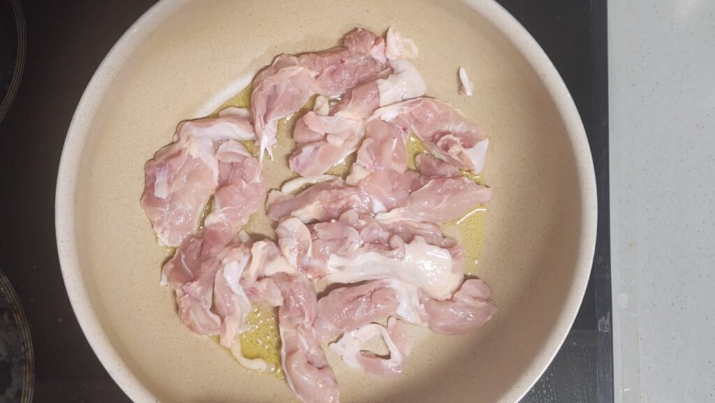Cooking skin-on chicken thigh in a pan with olive oil, starting skin-side down.