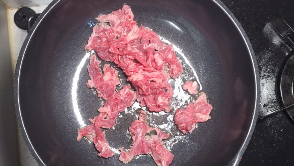 Briefly cooking thinly sliced beef in oil over medium heat before adding the vegetables.