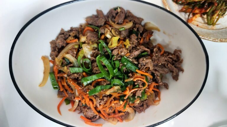 Cooking the beef and vegetables in the sauce until the beef is fully cooked, then finishing with a drizzle of sesame oil.
