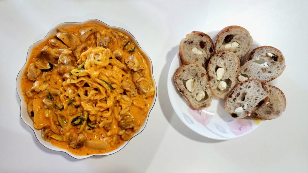 Finished Rosé Buldak jjimdak with chicken thigh, ramen, onion, and Korean green onion in a creamy milk and cheddar sauce.