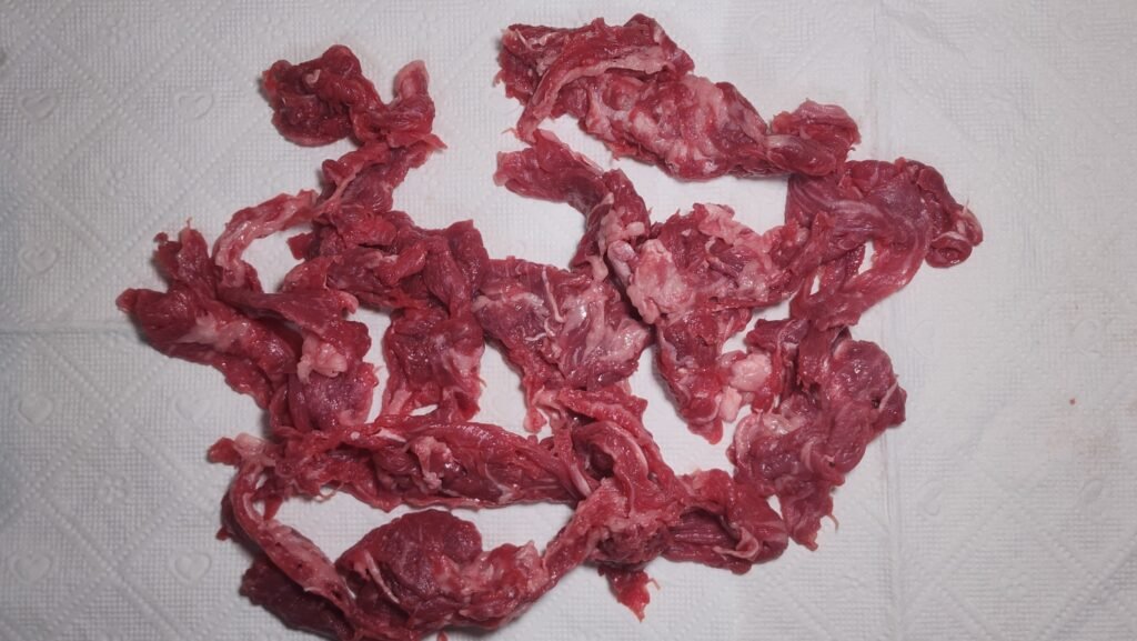 Patting thinly sliced beef dry with paper towels before cooking.