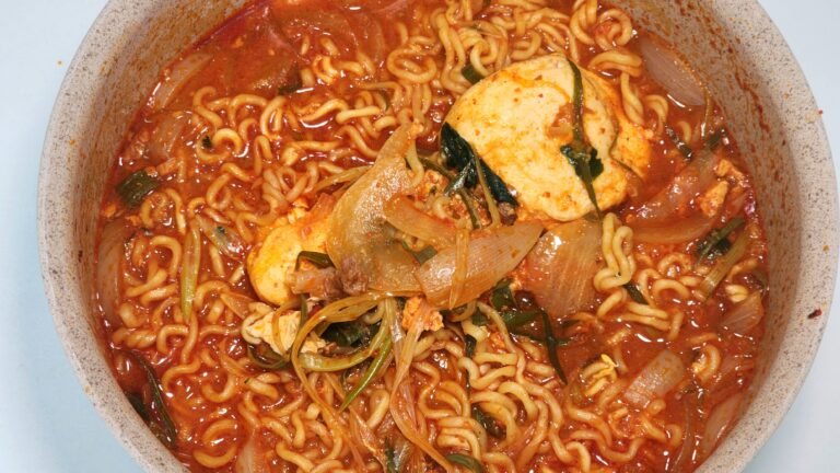 A finished bowl of spicy Shin Ramyun with green onion, onion, garlic, and gochugaru.