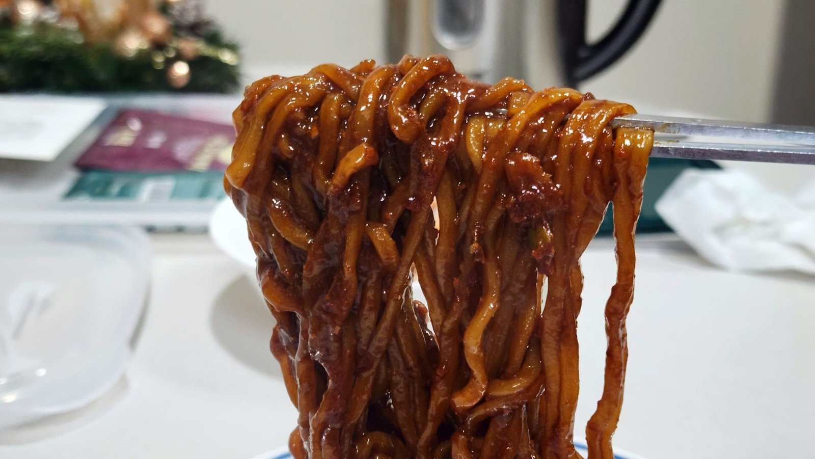 Spicy microwave Chapagetti served in a bowl, coated in glossy black bean sauce and chili oil